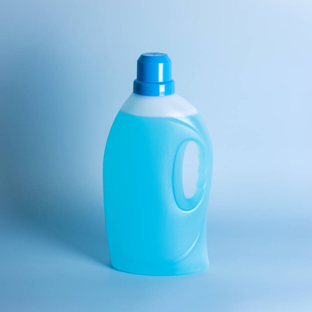 Botella de detergente sobre fondo azul, espacio para texto. Envase de plástico de producto de limpieza, productos químicos domésticos o detergente líquido para ropa. Lavandería, concepto de limpieza
. - Foto, imagen