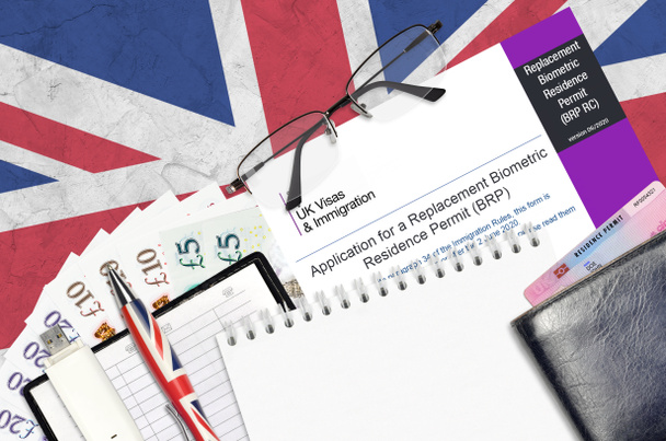 Englanninkielinen lomake BRP RC Hakemus korvaavalle biometriselle oleskelulupakortille Yhdistyneen kuningaskunnan viisumeilta ja maahanmuuttoviranomaisilta on pöydällä toimistoesineiden kanssa. Yhdistyneen kuningaskunnan oleskelulupapaperityöprosessi - Valokuva, kuva