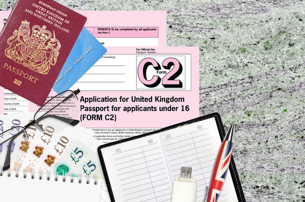 Modulo inglese C2 Domanda di passaporto per il Regno Unito per i candidati sotto i 16 anni si trova sulla tabella con articoli per ufficio. Passaporto del Regno Unito processo di lavoro - Foto, immagini