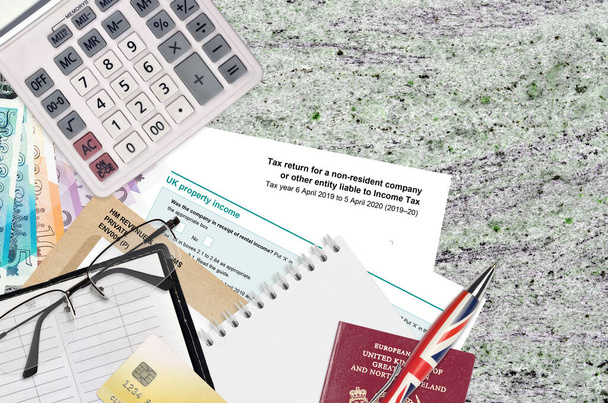 Das englische Formular sa700 Steuererklärung für ein gebietsfremdes Unternehmen oder eine andere Körperschaft, die der Einkommensteuer aus HM-Einnahmen und Zöllen unterliegt, liegt zusammen mit Bürogegenständen auf dem Tisch. HMRC Papierkram und Steuerzahlungsprozess - Foto, Bild