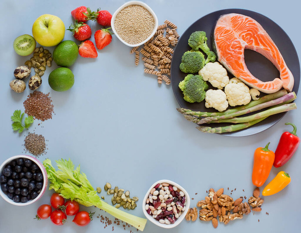 Balanced diet food frame background. Fresh vegatables, fruits, cereals, seeds and nuts on a blue background. Food frame with copy space - Photo, Image