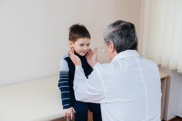 A young boy is listened to and treated by an experienced doctor in a modern clinic. A virus, and an epidemic - Foto, afbeelding