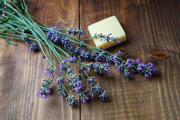 Spa massage setting with lavender flowers, soap on wooden background. - Фото, зображення