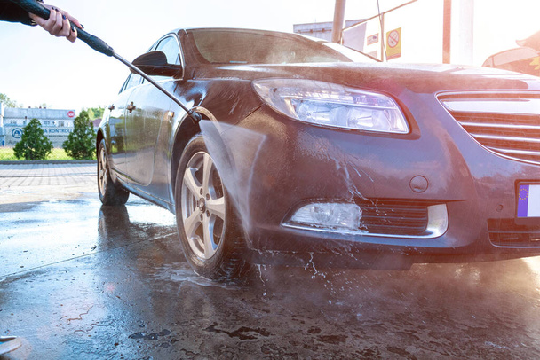 Service schone auto. Carwash met water, zeep. Auto van schuim. Voorzichtigheid met was onder druk. - Foto, afbeelding