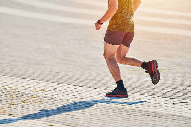 Juokseva mies. Urheilija lenkkeilee urheiluvaatteissa kaupungin tiellä. Terveellinen elämäntapa, kuntoiluharrastus. Street harjoitus, sprinting ulkona - Valokuva, kuva