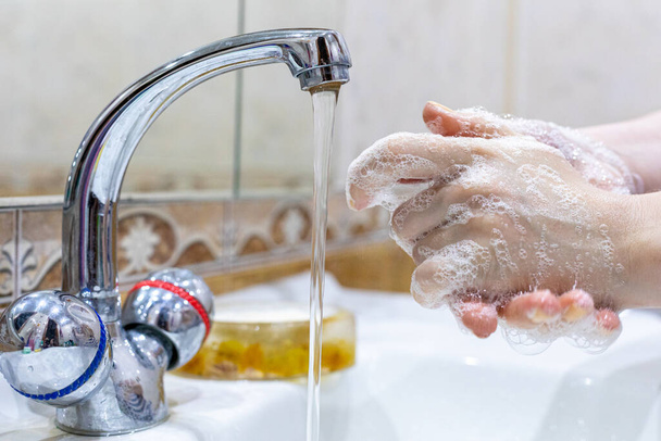 Tyttö pesee kätensä saippualla hanan alla vedellä. Henkilökohtainen hygienia. Desinfiointi. Hygieniakysymys. Koronavirus Sepelvaltimoviruksen leviämisen estäminen. - Valokuva, kuva