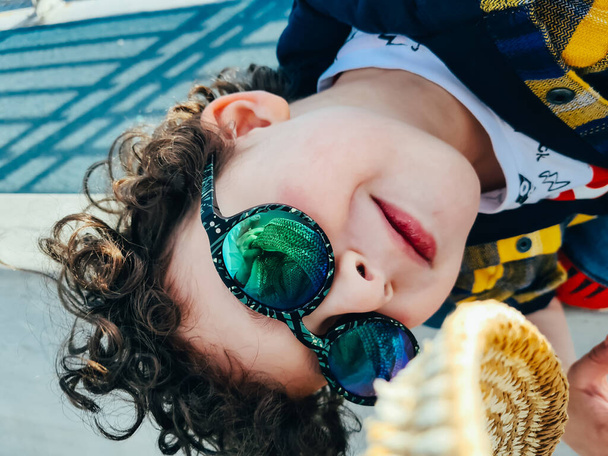 Стильный мальчик с открытыми глазами в солнцезащитных очках развлекается
. - Фото, изображение