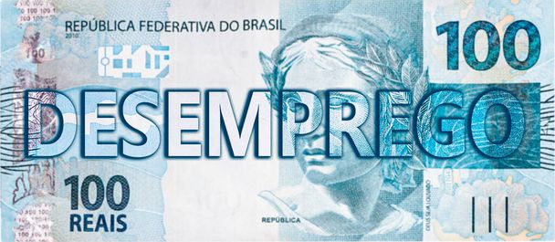 100 Brazilian reais note with the word UNEMPLOYMENT written in the spotlight. Concept of economic collapse, loss and recession. - Photo, Image
