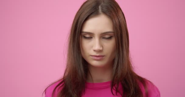 Unhappy woman dressed in pink t-shirt posing in studio - Кадры, видео
