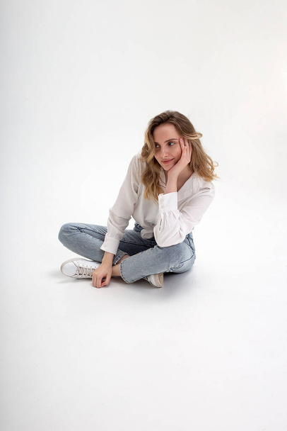 young cute smiling caucasian girl posing in white shirt, blue jeans at studio - Foto, imagen