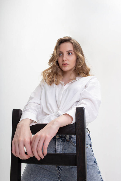 jovem bonito menina branca pensativa posando em camisa branca, jeans azul no estúdio
 - Foto, Imagem