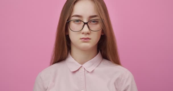 Charming girl in eyeglasses smiling over pink background - 映像、動画