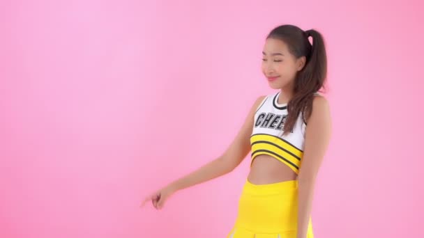 close-up footage of beautiful young Asian woman in cheerleader uniform isolated on pink - Video