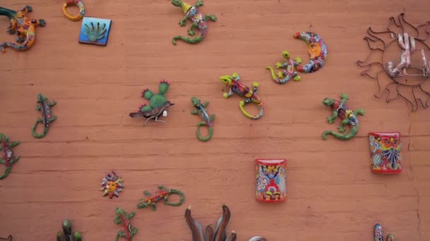 Barevné keramické mexické umělecké díla visí na cihlové zdi v Tubac, Arizona  - Záběry, video