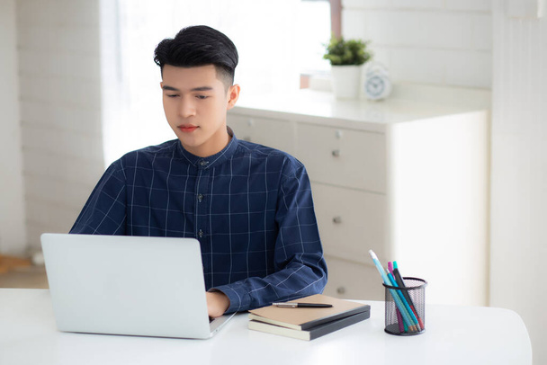 Молодой бизнесмен работает из дома с ноутбуком на столе, внештатный мужчина сидит дома, используя ноутбук для связи и отдыха на столе, предприниматель в стартап-бизнесе, новая нормальная. - Фото, изображение