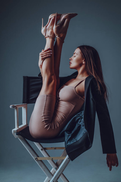 Young sexy woman in business clothing doing fitness stretching in chair - Фото, изображение
