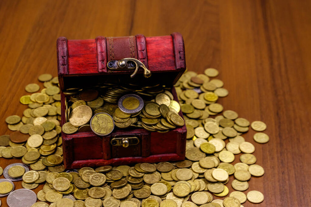 Vintage skrzynia pełna złotych monet na drewnianym tle - Zdjęcie, obraz