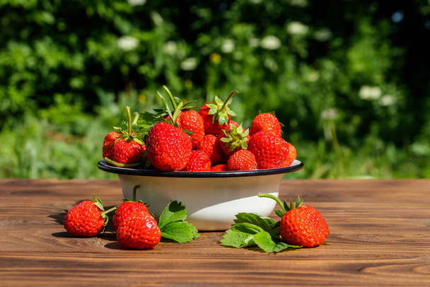 Fresh ripe strawberry on a wooden table outdoor - Foto, afbeelding