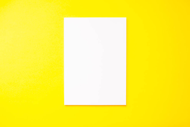 A4 blank white sheet on a bright yellow background. Mockup - Φωτογραφία, εικόνα