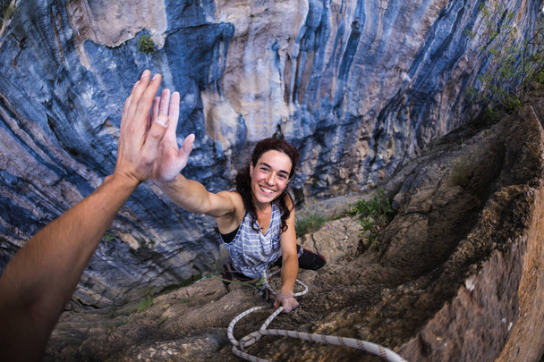 Uma mulher está subindo na Turquia, mulher turca sobe a rocha, Passatempo extremo, Superando uma rota de escalada difícil, Superando o medo de alturas, Menina emocional dá cinco a um amigo
. - Foto, Imagem