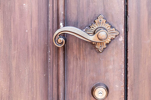 Cerrar - hasta Abrepuertas de latón clásico antiguo y puerta de madera marrón
 - Foto, Imagen
