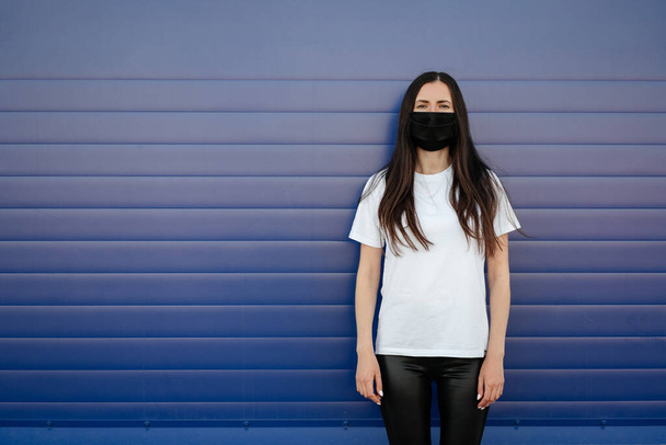Woman wearing a mask due to air pollution or a virus outbreak in the city. On a blue background. Corona virus concept. - Photo, Image