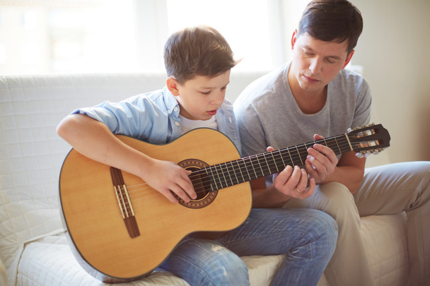 Uomo che insegna a suo figlio a suonare la chitarra
 - Foto, immagini
