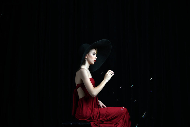 piękna dziewczyna w czarny kapelusz łapie bańki mydlane i myśli życzenia - Zdjęcie, obraz