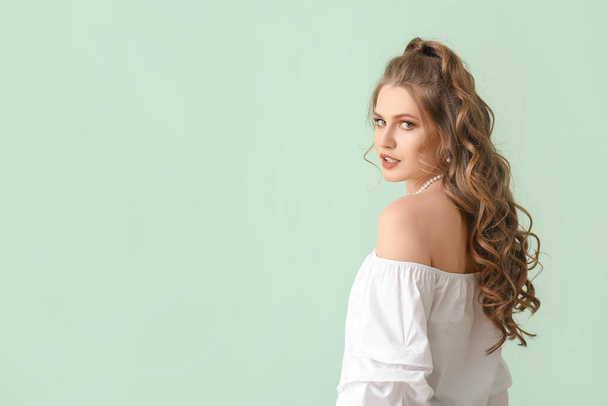 Beautiful young woman with stylish hairdo on color background - Фото, зображення