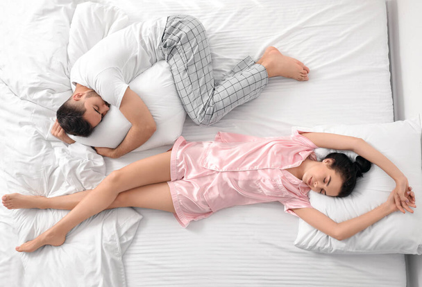 Νεαρό ζευγάρι κοιμάται στο κρεβάτι, κορυφαία άποψη - Φωτογραφία, εικόνα