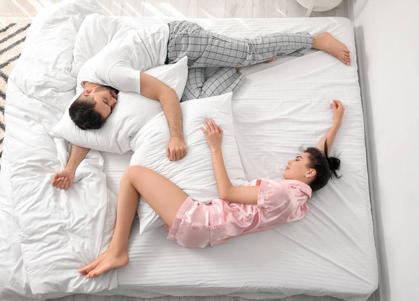 Νεαρό ζευγάρι κοιμάται στο κρεβάτι, κορυφαία άποψη - Φωτογραφία, εικόνα
