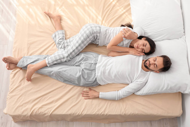 Jeune couple dormant au lit, vue sur le dessus - Photo, image
