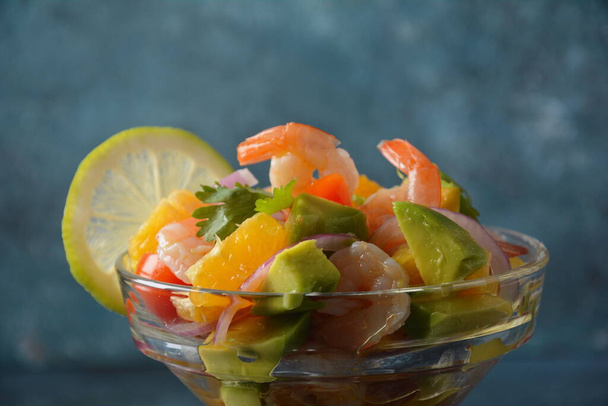 Ceviche salad with shrimps, oranges and avocado in glass bowl on a dark or grey background. Latin American food. Delicious, freshly made shrimp ceviche. Shrimp marinated in lime and orange . - Foto, Imagem