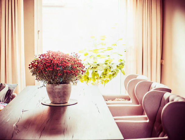 Beautiful living room with Chrysanthemums flowers bunch on dinner table at window  background. Autumn home decoration - 写真・画像
