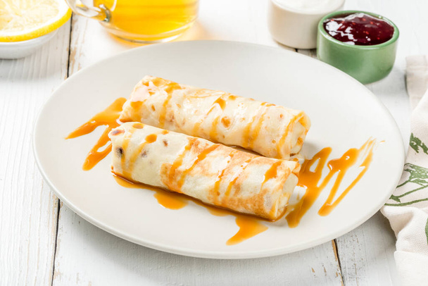 Breakfast stuffed pancakes on a white, round plate. Close-up shot - 写真・画像