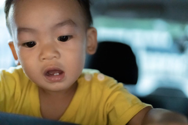 1 An Adorable garçon asiatique jouant et regardant autour dans le portrait de voiture. Jouer en famille et apprendre en lieu sûr pour enfant Concept. Vue de face Vue de face Fermeture Espace de copie, et arrière-plan flou. - Photo, image