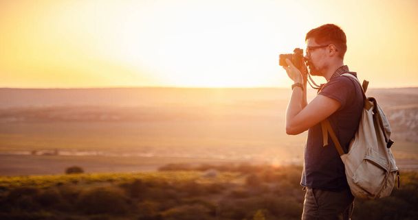 Mies valokuvaaja reppu ja kamera ottaa kuvan auringonlaskun vuoret Travel Lifestyle harrastus käsite seikkailu aktiivisia lomia ulkona - Valokuva, kuva