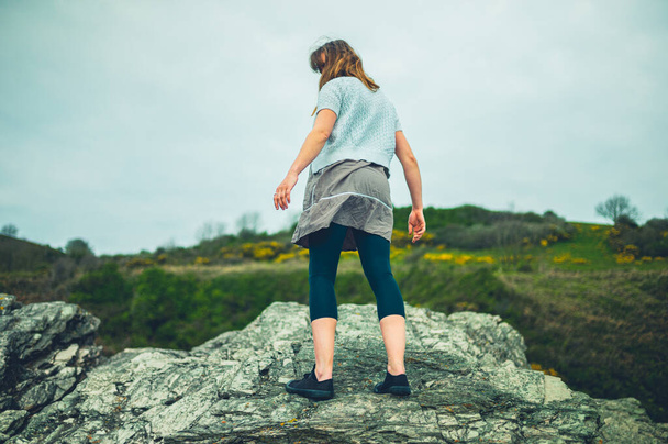 A young woman is standing on rocks in the countryside - Photo, Image