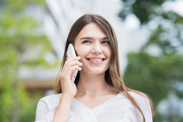 Mladá obchodní žena venku, mluví s chytrým telefonem na ucho - Fotografie, Obrázek