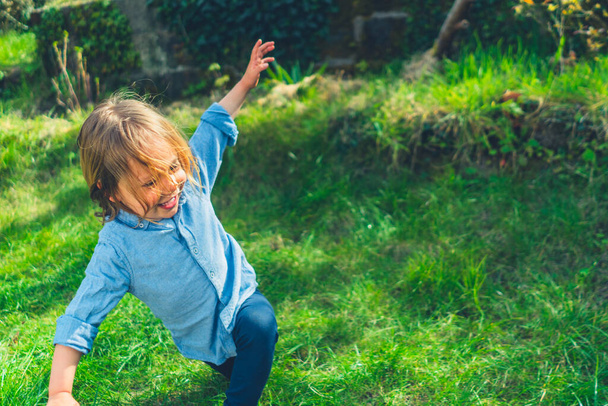 A little preschooler is chasing bubbles in the garden on a sunny spring day - Foto, Bild
