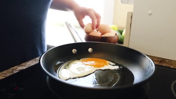 Close-up of Frying Tasty Fried Eggs in Hot Pan with oil. Mothers Female Hand Breaks Chicken Egg Over Kitchen. Family Breakfast. - Záběry, video