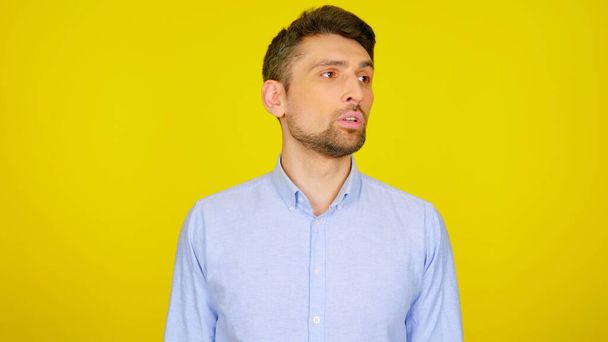 Handsome bearded man looks away on a yellow background with copy space - Photo, Image