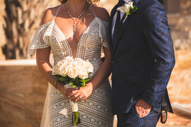 krásné svatební šaty na nevěstu, žena drží květiny kytice a stojí v blízkosti ženicha  - Fotografie, Obrázek