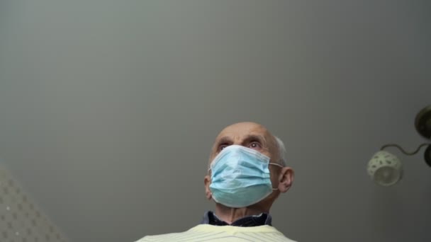 senior man in disposable mask and yellow pullover walks - Filmagem, Vídeo