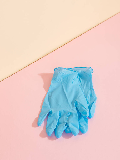 黄色のピンクの背景に青い医療用手袋。病気に対する保護の概念。スペースのコピー. - 写真・画像