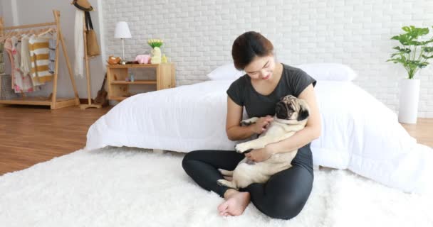 Beautiful Asian young woman playing with her dog and smile with dog pug breed looking in funny and serious face in bedroom feeling so happiness and relaxation,Dog Friendship Concept - Felvétel, videó