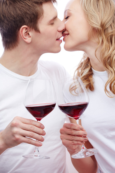 Pareja sosteniendo vino tinto y besándose
 - Foto, imagen