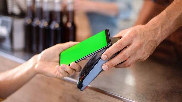 Young Woman is Using Her Smartphone with Green Screen for Contactless Payment. She is Paying for Gourme Street Food. Eco Friendly Gluten Free Food Court Selling Modern Fusion Cuisine - Photo, image