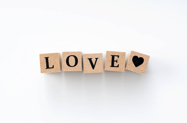 A wooden block with the word LOVE written on it on a white background - Foto, imagen