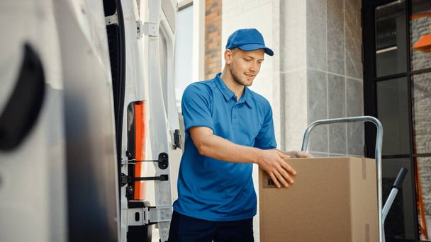 Delivery Man Uses Hand Truck Trolley Full of Cardboard Boxes and Packages, Loads Parcels into Truck Van. Professional Courier Loader helping you Move, Delivering Your Purchased Items Efficiently - Фото, изображение